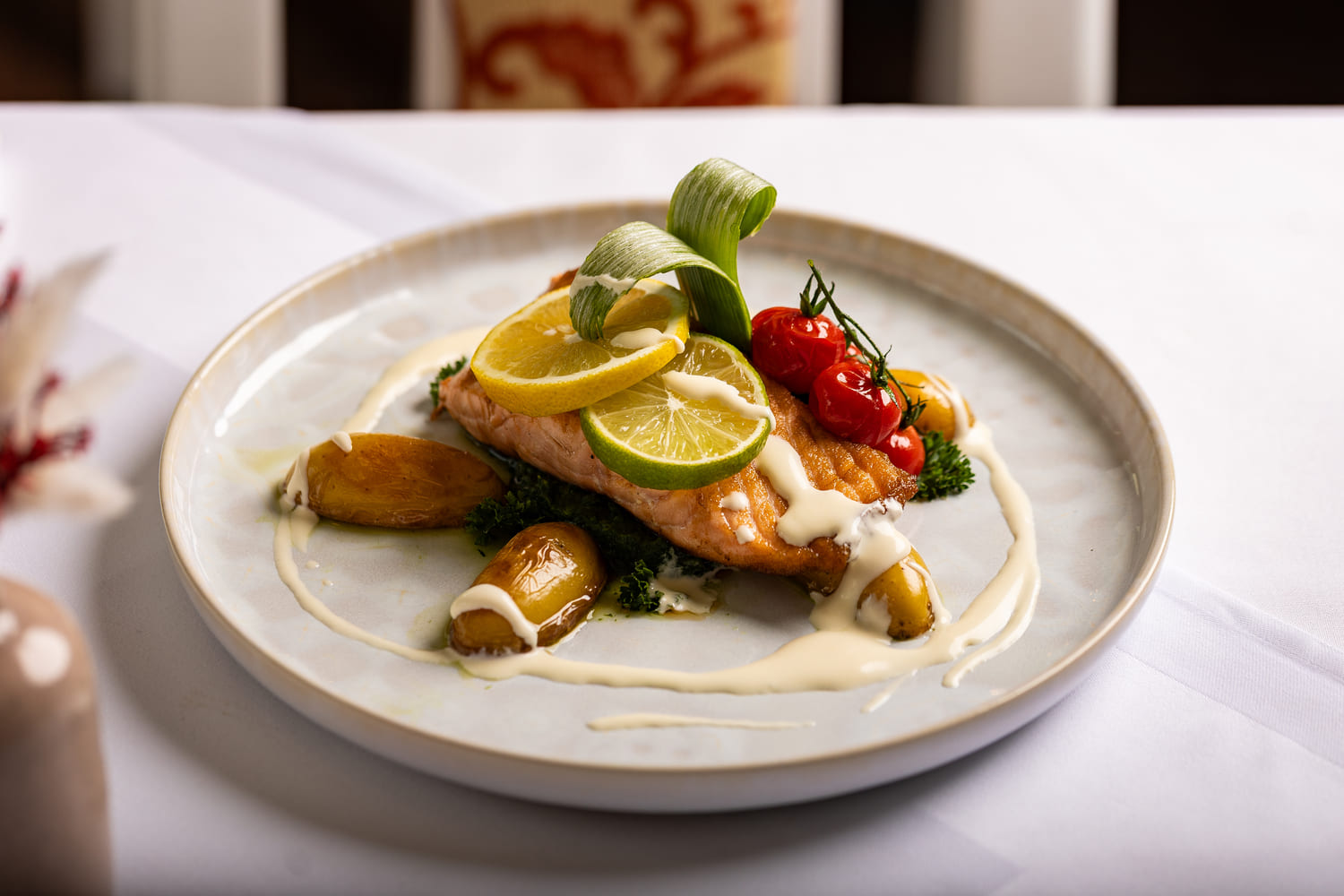 Gebratenes Lachsfilet mit Zitronen- und Limettenscheiben, cremiger Sauce, Röstkartoffeln und Kirschtomaten.